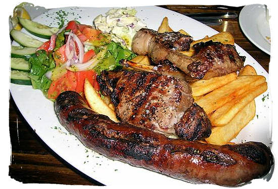 Grilled boerewors (sausage), steak and lamb chops with fried potato chips and salads, typical South African boerekos (farm house cooking) - South African traditional food